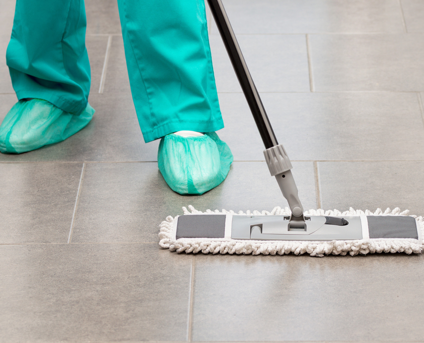 Low Front View Of A Medical Cleaner In Protective Gear Mopping Facility Floor
