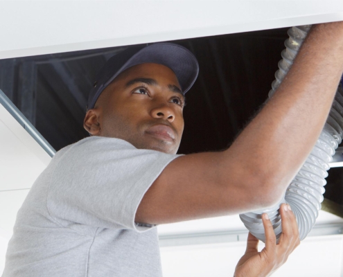Janitor Vacuuming Vents In Ceiling